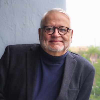 Picture of Lisandro Pérez wearing a black sports jacket, a turtleneck, and looking directly at the viewer.