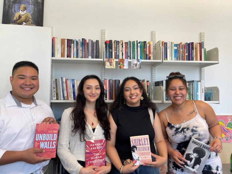 Four young people posing and holding a book